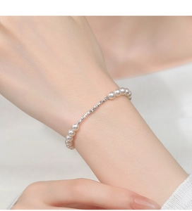 Detail view of refined S925 silver bracelet with elegant white pearls on model wrist