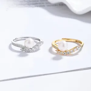 Detail of V-shaped open rings with fresh water pearls and small zircons in gold and silver