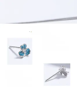 Macro detail of silver iris stud earrings with blue enamel petals and zircon center