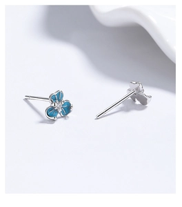Macro view of sterling silver iris flower studs with blue enamel and zircon detail