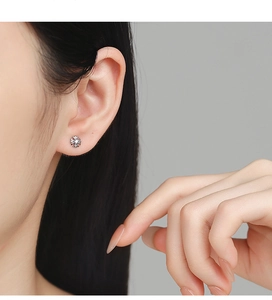 Detailed view of sterling silver cross stud earring with zircon on ear cartilage