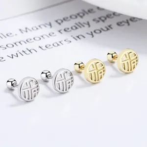 Detailed view of silver and gold Fu character stud earrings with screw ball backs