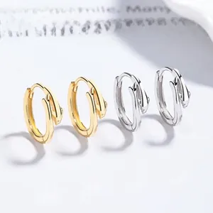 Detail of silver and gold dolphin-shaped hoop earrings with a sleek fish tail clasp design