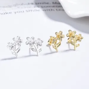 Macro detail of silver and gold flower stud earrings with zircon floral design
