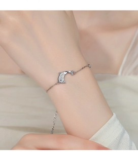 Macro detail of a 925 sterling silver dolphin bracelet with LOVE engraving on a wrist