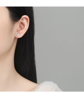 Close-up of model wearing small S925 sterling silver daisy flower stud earring