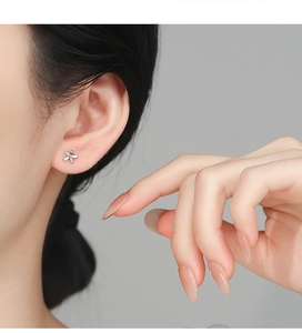 Close-up of 925 silver flower stud earring with zircon accents on a female model's ear