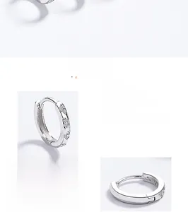 Macro detail of 925 sterling silver hoop earrings with butterfly carving and zircon
