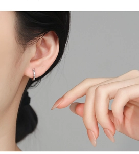 Close-up of 925 silver hoop earrings with cubic zirconia on a female model's ear