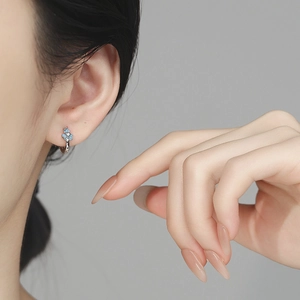 Boucles d'oreilles iris bleu en argent 925 portées élégamment sur une oreille féminine