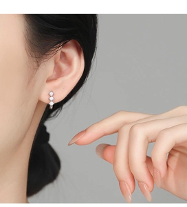 Detail of 925 sterling silver hoop earrings with three cubic zirconia stones on model