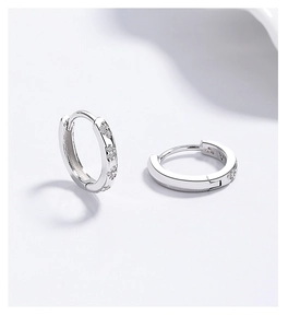 Close-up of 925 silver huggie earrings with sparkling zircon star clusters and secure clasp