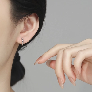 925 silver huggie hoop earrings with white zircon crystals worn by a model in close-up view