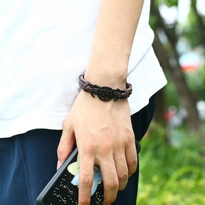 Retro nautical braided leather bracelet with black ship wheel charm on male wrist