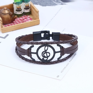 Dettaglio del bracciale in pelle intrecciata marrone con ciondolo nota musicale nera