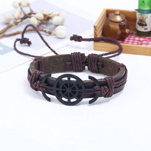 Close-up of vintage brown leather bracelet with black anchor and helm charms