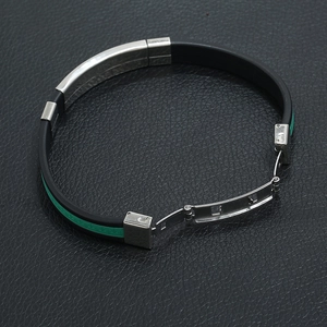 Macro detail of men's black silicone bracelet with green Greek key pattern and steel clasp