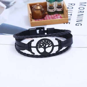 Detail of multi-layer braided leather bracelet featuring a black tree-shaped metal charm