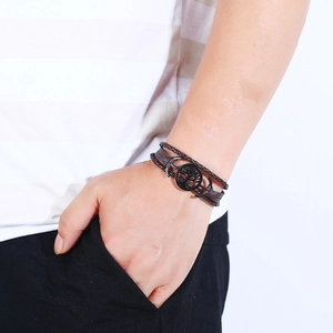 Multilayer brown leather bracelet with tree of life and anchor charms on model's wrist