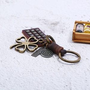Retro braided leather keychain featuring a bronze four-leaf clover pendant and metal charms