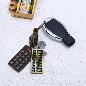 Retro handmade braided leather keychain with vintage metal abacus and charms on stone surface