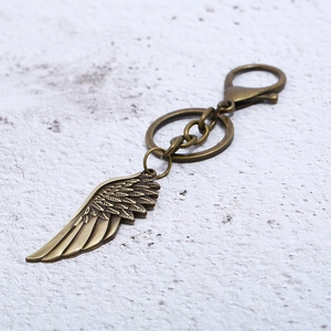Close-up of vintage bronze wing keychain with detailed feather texture and lobster clasp