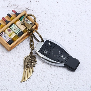 Macro detail of bronze feather wing charm attached to a modern car key remote shell