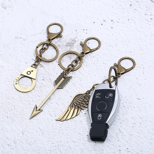 Vintage bronze alloy keychain set featuring handcuffs, arrow, and wing charms for bags
