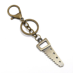 Detail of vintage bronze alloy keychain featuring a mini hand saw tool pendant charm