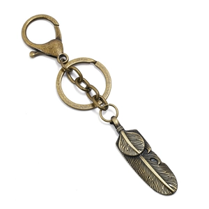 Detail view of a vintage bronze feather keychain charm with detailed metal texture