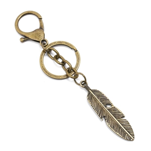 Macro detail of retro bronze feather pendant keychain with alloy lobster clasp