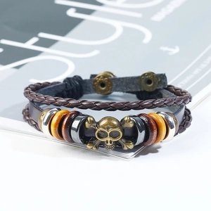 Detail of vintage braided leather bracelet featuring a bronze skull and multi-layer cord