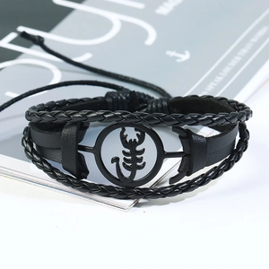 Détail macro d'un bracelet pour homme en cuir avec breloque scorpion noire et cordons tressés