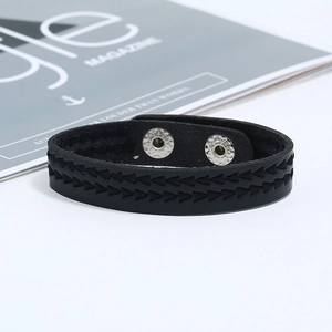 Détail du bracelet en cuir noir tressé avec surpiqûres en zigzag et boutons-pression