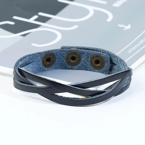 Close-up of black layered leather bracelet with three adjustable bronze snap buttons