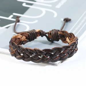 Dettaglio di un bracciale in pelle intrecciata marrone scuro con cordoncini regolabili su rivista