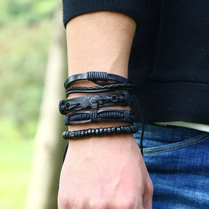 Détail de bracelets en cuir tressé noir et perles portés sur un poignet masculin
