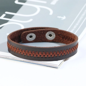 Dettaglio del bracciale largo in pelle marrone scuro con bottoni a pressione in metallo