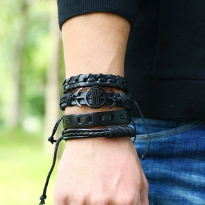 Gros plan d'un lot de 4 bracelets en cuir tressé noir avec breloques Main de Fatma et ancre