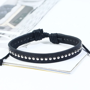 Detail of black leather punk bracelet with silver metal studs and woven pull rope