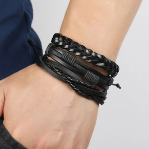 Close-up of a four-piece black leather bracelet set featuring woven cords on a male wrist