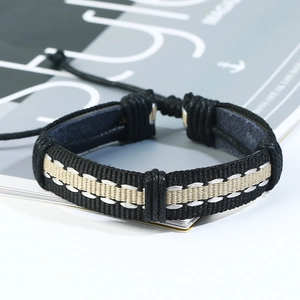 Close-up of black and beige woven leather bracelet with adjustable cord on white desk