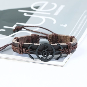 Dettaglio di un bracciale punk in pelle con chiave di violino in metallo su pelle intrecciata