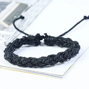 Macro detail of black braided cord bracelet featuring an adjustable slide knot closure
