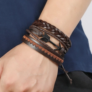 Close-up of multilayer leather bracelet with braided cord and metal arrow charm detail