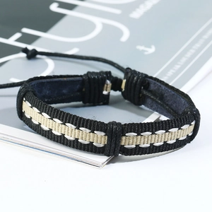 Détail du bracelet en cuir tressé noir avec surpiqûres blanches et cordon ajustable