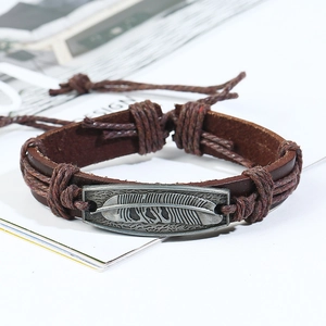 Detail of vintage braided leather bracelet with a silver metal feather charm and cord