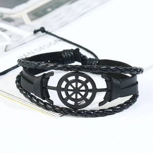 Détail d'un bracelet multicouche en cuir noir avec un pendentif gouvernail nautique