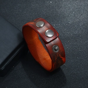 Close-up of retro brown leather bracelet featuring adjustable silver snap buttons