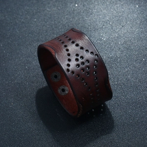 Detail of vintage brown leather wide cuff bracelet with cutout patterns and metal snaps